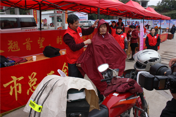 梧州市總工會的黨員義工們在市東出口春運服務(wù)站助力&ldquo;摩托大軍&rdquo;平安返鄉(xiāng)，幫助他們檢查車輛和行李，穿上雨衣。--黃賀峰攝.j